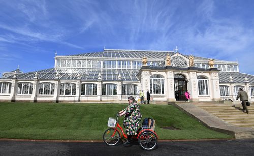 A woman cycles past the newly restored Victorian Temperate House in Kew Gardens. (AAP)