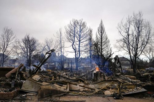 A fire still burns in a home destroyed by the Marshall Wildfire in Louisville.