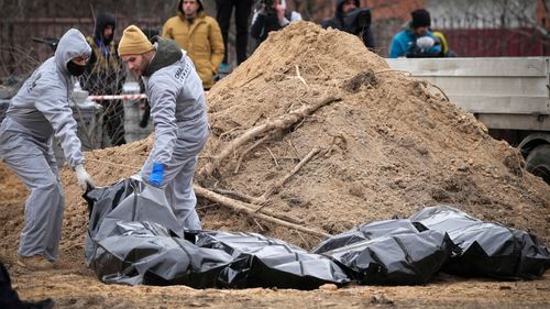 Men wearing protective gear exhume the bodies of civilians killed during the Russian occupation in Bucha, in the outskirts of Kyiv, Ukraine, Wednesday, April 13, 2022. 