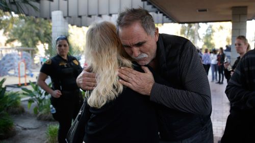  A man hugs a person who was near a shooting rampage at a social services center that killed multiple people and wounded others. (AAP)
