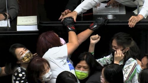 Opposition Nationalist party lawmaker Chen Yu-jen, in white shirt, is grabbed by ruling Democratic Progressive Party lawmakers as she tries to climb onto the podium during a parliament session in Taipei. 