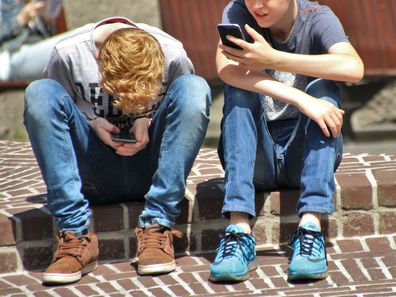 Stock image of two young boys on their phones.