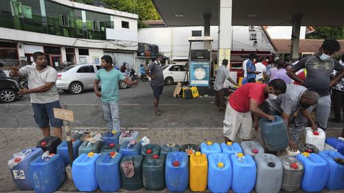 Sri Lankans gather at a fuel station to buy diesel before the beginning of curfew in Colombo after a state of emergency was declared by the President. 