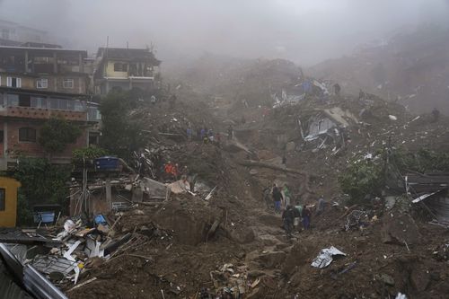 Salvatori și rezidenți caută victime într-o zonă afectată de alunecări de teren din Petropolis, Brazilia, miercuri, 16 februarie 2022. 