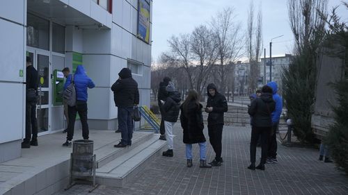 People queue to use an ATM machine outside in Sievierodonetsk, the Luhansk region, eastern Ukraine, Thursday, Feb. 24, 2022. Russian President Vladimir Putin on Thursday announced a military operation in Ukraine and warned other countries that any attempt to interfere with the Russian action would lead to "consequences you have never seen." (AP Photo/Vadim Ghirda)