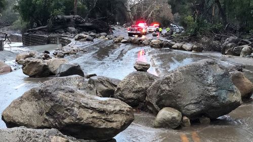Santa Barbara County Firefighters work admist flood waters and debris flow during heavy rains in Montecito on Tuesday. (AAP)