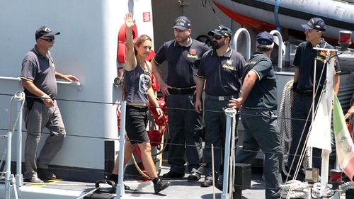 Sea-Watch 3 captain Carola Rackete, from Germany, waves as she arrives in the Sicilian port of Porto Empedocle, escorted by Italian finance police on Monday, July 1.