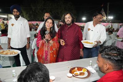 This photograph released by the Reliance group shows Reliance Industries Chairman Mukesh Ambani's son and groom Anant Ambani, center right, and bride Radhika Merchant, center left interacting with guests during a community food service held as part of their pre-wedding celebrations at Jogvad village near Jamnagar, India, Wednesday, Feb.28, 2024. (Reliance group via AP)