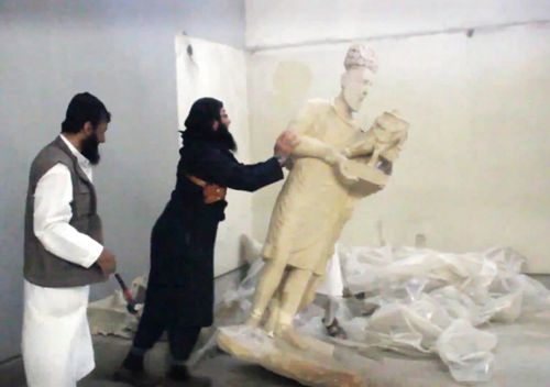 File photo taken on February 26, 2015 allegedly showing an IS militant pushing a statue inside the Mosul museum. The picture was released by the Media Office of the Nineveh branch of the Islamic State (IS) Group.
