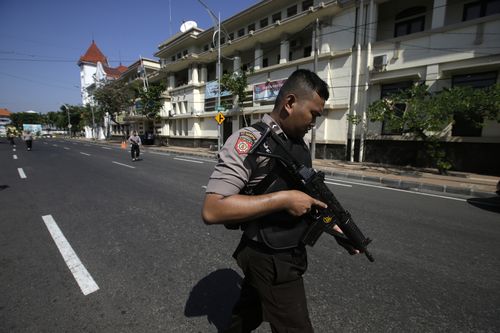 Heavily armed officers block a road in Surabaya leading to the local police headquarters, where another bomb was detonated. (AAP)