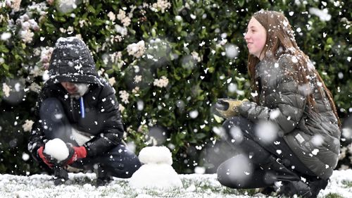 Brody Mielke, left, 10, and his older sister Braelynn, 12, make a snowman in front of their California home.
