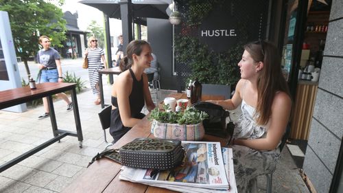 Two young women enjoy a catch up on King William Road in Hyde Park in Adelaide.