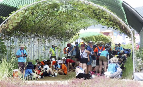 Attendees of the World Scout Jamboree beat the heat under a vine tunnel at a campsite in Buan, South Korea, Friday, Aug. 4, 2023. 