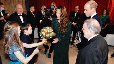 Catherine, Duchess of Cambridge is given a posy by 10 year old Poppy Clee and Rowan Clarke during the Royal Variety Performance 