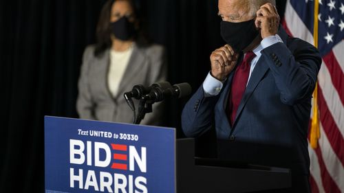 Democratic presidential candidate former Vice President Joe Biden joined by his running mate Sen. Kamala Harris, D-Calif., replaces his face mask after speaking at the Hotel DuPont in Wilmington, Delaware.