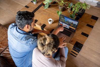 Happy couple at home booking a trip online using their laptop computer
