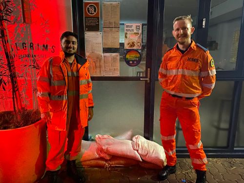 Volunteers place sandbags outside businesses in Bronte  as a blocked drain causes waters to rise.