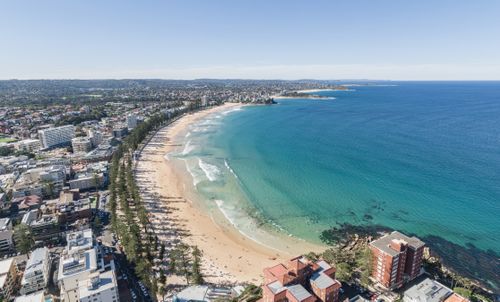 Panoramic high angle aerial drone shot of famous Manly Beach, a beach-side suburb of northern Sydney in the state of New South Wales, Australia. Northern Beaches in the background.
