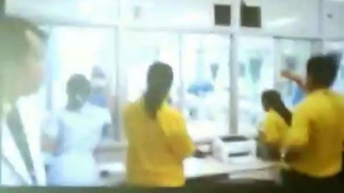 Parents wearing yellow shirts look through a glass window at their sons in hospital. Picture: Twitter