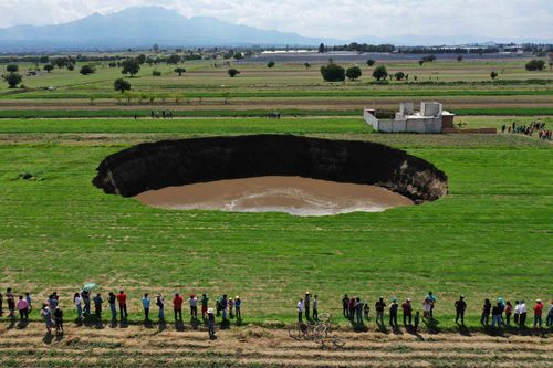 People gather to look at the giant sinkhole that opened up this week in central Mexico. 