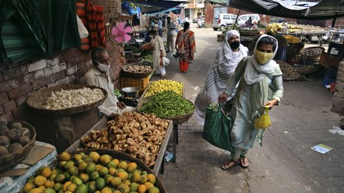 People wearing face masks as a precaution against the coronavirus walk after buying vegetables at market in Jammu, India.