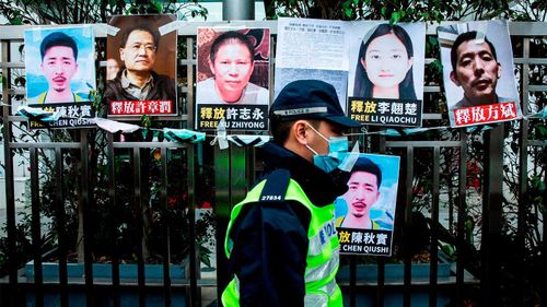 Un oficial de policía pasa junto a carteles que piden la liberación de los activistas de derechos humanos chinos que han sido registrados en la valla de la Oficina de Enlace con China en Hong Kong.