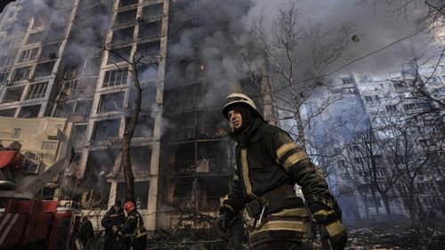 A firefighter walks outside a destroyed apartment building after a bombing in a residential area in Kyiv.