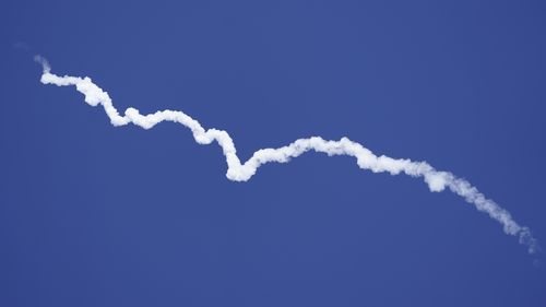 Blue Origin's New Shepard rocket leaves a smoke trail after lifting off.