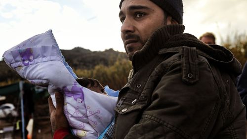 A migrant holding his baby, arrives along with other migrants and refugees, on the Greek island of Lesbos.  (AFP)