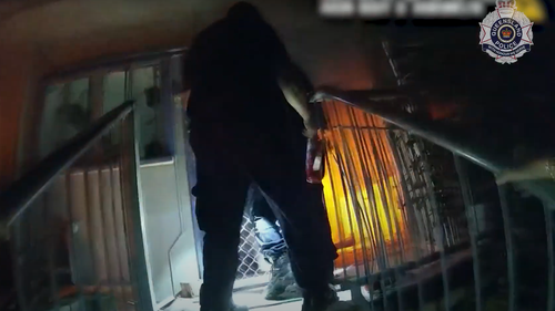 Dramatic vision has captured the moment police officers rescued an elderly couple, one of whom was in a wheelchair, and their grandson from flames that engulfed their home on the Gold Coast.