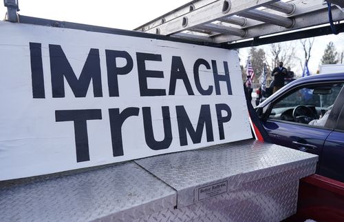 A sign stands in the box of a pickup truck during a gathering calling for the impeachment of President Donald Trump at South High School before a car rally through the streets of downtown Sunday, Jan. 10, 2021, in Denver. (AP Photo/David Zalubowski)