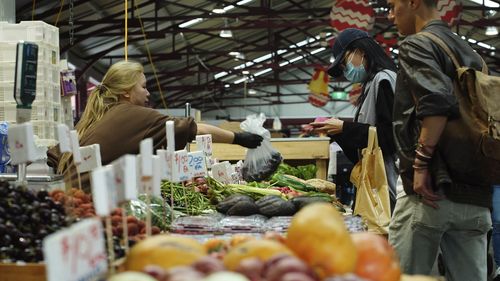 General photo of people shopping for fruits and vegetables at the Queen Vic Market.