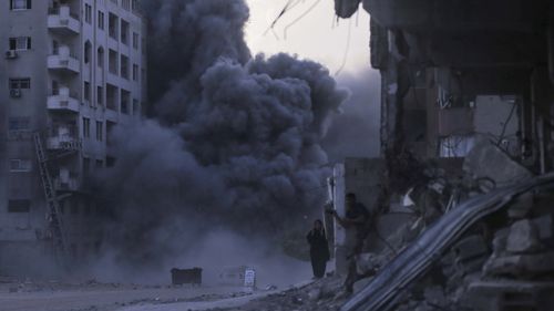 Palestinians take cover during an Israeli strike on a building in Gaza City, Sunday, Sept. 7, 2025, after the Israeli army issued a prior warning.