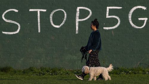 Una donna in Inghilterra passa davanti a una lettera di graffiti contro la quinta generazione.