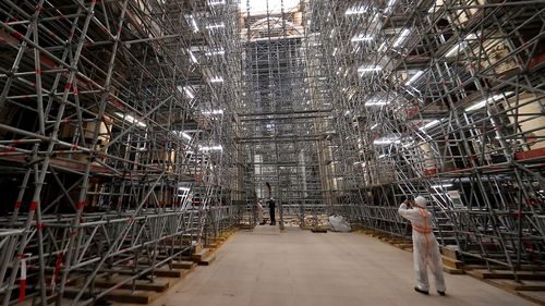 A worker takes a picture of the scaffolding's at the reconstruction site ahead a visit of the French president at the Notre-Dame de Paris Cathedral, in Paris, Friday, April 15, 2022.
