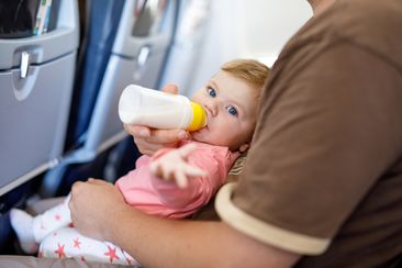 Dad holding his baby daughter during flight on airplane going on vacations. 