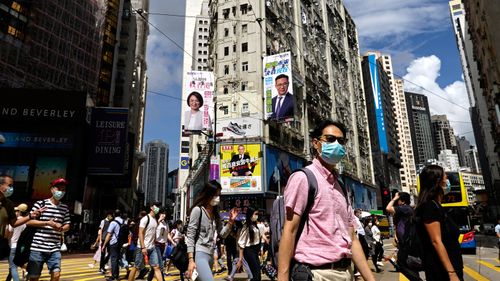 People wearing face masks walk on a downtown street in Hong Kong