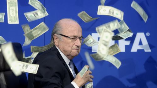 FIFA president Sepp Blatter reacts while banknotes are thrown at him during a press conference. (AAP)