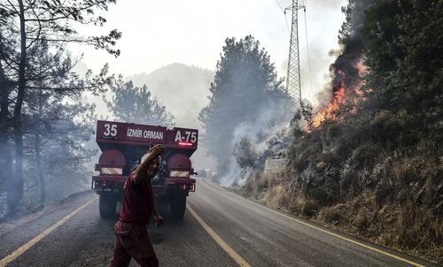 Firefighters work as the wildfires engulf an area near the seashore, forcing people to be evacuated by boats, in Bodrum, Mugla, Turkey, Sunday, Aug. 1, 2021.  (Ismail Coskun/IHA via AP)