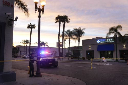 A police officer ties tape around a light pole near where a mass shooting targeted a Lunar New Year party. 