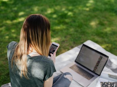 Stock image of a young girl on a phone and laptop.