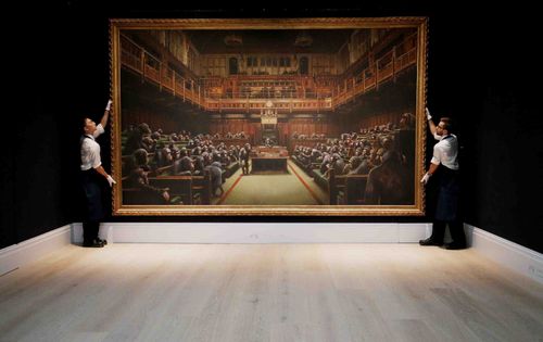 British artist Banksy's "Devolved Parliament," a satirical oil painting depicting the House of Commons filled with chimpanzees, has sold at auction in London for a record-breaking £9,879,500 ($12,200,000). Full credit: Jonathan Brady/PA Images via Getty Images