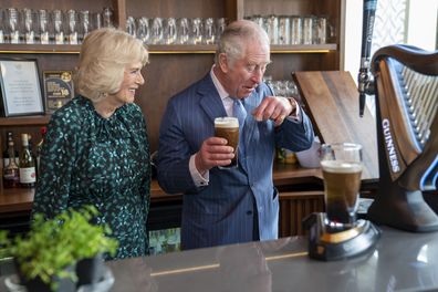 Prince Charles wipes Guinness froth off the tip of his nose after Camilla, Duchess of Cornwall points out the royal had some on his face during a visit to the Irish Cultural Centre to celebrate the Centre's 25th anniversary in the run-up to St Patrick's Day