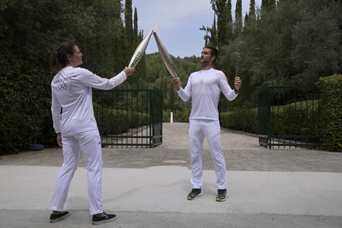 The first torch bearer, Greek olympic gold medalist Stefanos Douskos, right, passes the flame to first French torchbearer, three-time Olympic medallist Laure Manaudou