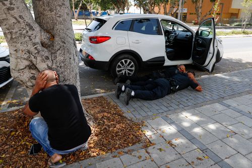 People take cover as a siren sounds a warning of incoming rockets fired from the Gaza strip, in the southern Israeli town of Ashkelon.