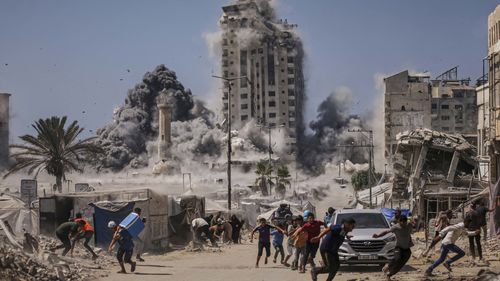 Palestinians run for cover during an Israeli airstrike on a high-rise building in Gaza City.