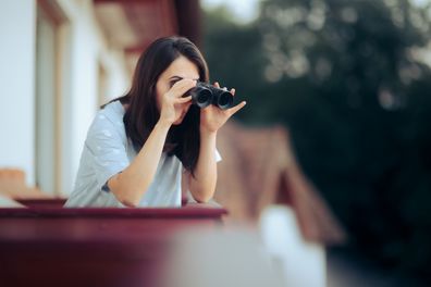 Woman snooping on neighbour from her balcony