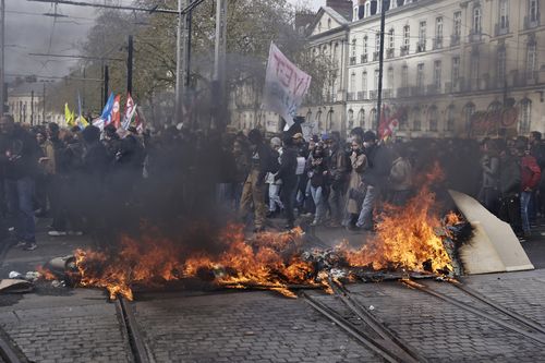 Demonstrators walk by a street fire during a protest Thursday, April 6, 2023 in Nantes, western France.