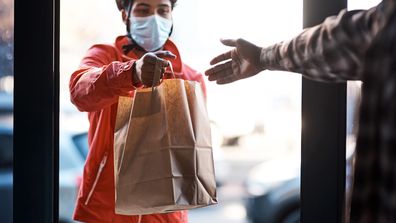 Shot of a masked man delivering a food package