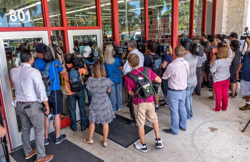 Members of the press crowd outside the Auto Zone parts store where two FBI agents interviewed a store employee in relation to the arrest.